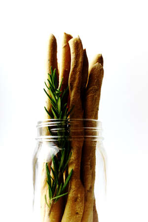 Italian Grissini with rosemary in a glass jar on a white background - verticalの写真素材