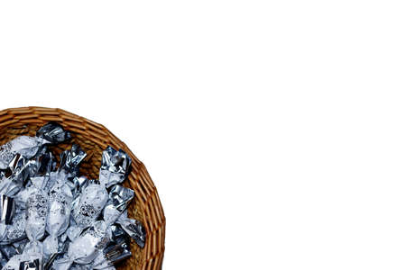 White and silver packaged Christmas chocolate candies in a brown wicker basket on a white background - left cornerの写真素材