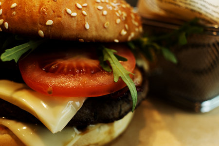 Close up of a juicy hamburger with melted cheese, tomatoes, and grilled meatの写真素材