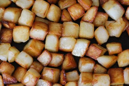 close up of baked potato cubes in pan in kitchenの写真素材