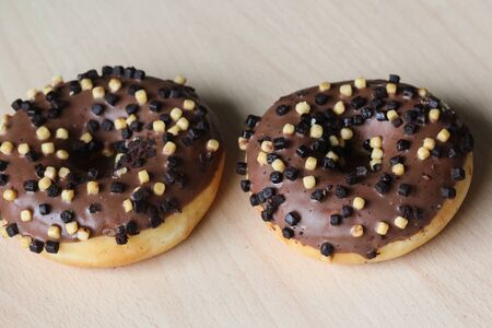 Close up of chocolate brownie donuts on table. The donuts is brown glazed with brownie partsの写真素材