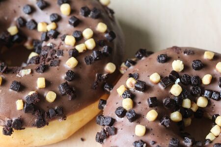 Close up of chocolate brownie donuts on table. The donuts is brown glazed with brownie parts