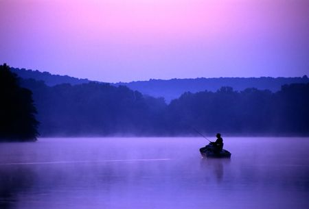 An angler spends a quiet morning on the lake fishing for bass.の写真素材
