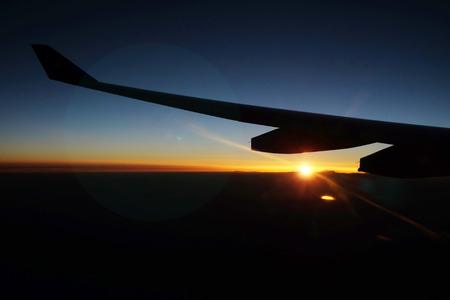 Sunrise at the skyline taken on the airplane with the left wing of the planeの写真素材