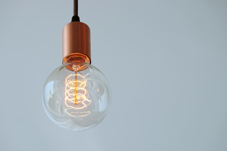 Vintage filament lamp with coil shape light hanging from the ceiling of white backgroundの写真素材