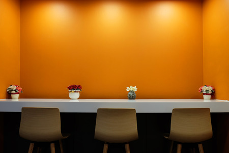 Office working bar for three wood seats with orange background decorated by flowers in small...
