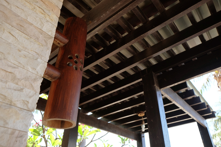 Wooden cylinder bulb lamp installed on the walkway with the background of roof tile over wood lathの写真素材