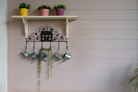 Three little tress in small yellow, pink and purple flowerpots with many watering pots for decoration on wooden pink wallの写真素材