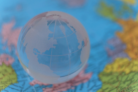 Transparent glass terrestrial globe model on the blurry international paper map