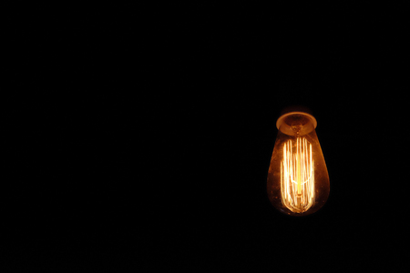 Vintage filament lamp hanging from the ceiling of dark backgroundの写真素材