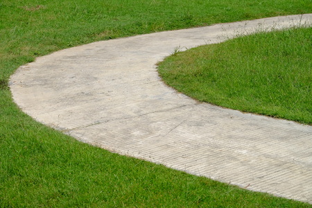 Round curve cement walkway in the fresh green grass gardenの写真素材