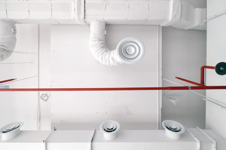 Bottom view of white air duct on the ceiling with red water sprinkler pipe andの写真素材