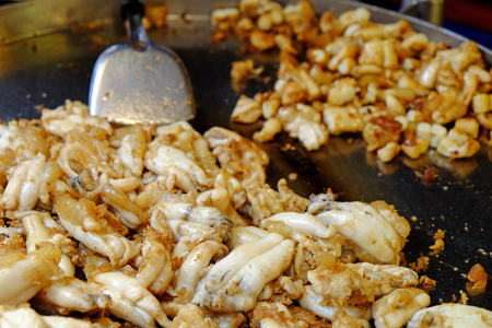 Cooking fried female squid with eggs on the black hot plateの写真素材