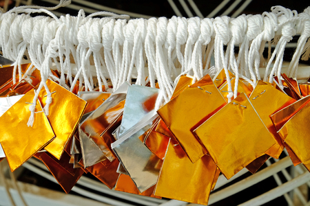 Silver and gold color glossy paper tied with white thread hanging in funfair for lucky draw gameの写真素材