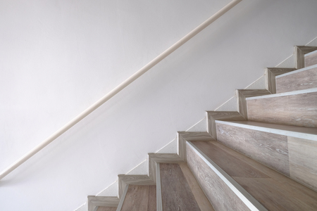 Side view of wooden stairs and handrail attached to the wallの写真素材