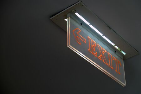 Perspective view of orange emergency fire exit sign hanging on the ceilingの写真素材