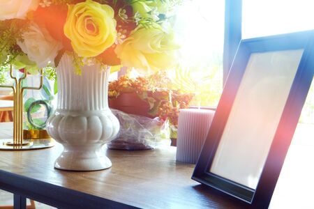 Empty photo frame on wood table decorated by flowers in vaseの写真素材
