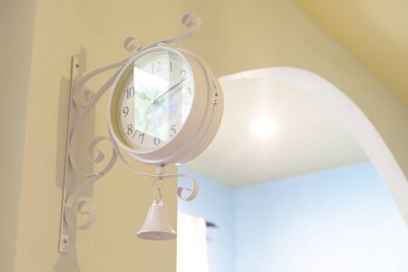 Classic round clock installed on a wall at the entrance of blue color wall room