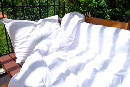 White pillow and blanket on wood sofa at outdoor balconyの写真素材