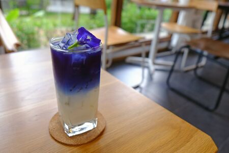 Fresh Asian pigeonwings juice over coconut milk with ice in glass on wood tableの写真素材