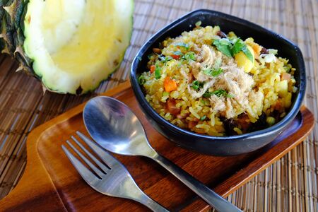 Pineapple fried rice served on wood tray with fresh half pineapple