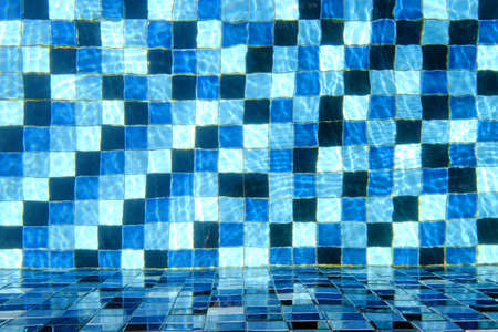 Top view of swimming pool tiled floor with the side wall through crystal clear waterの写真素材