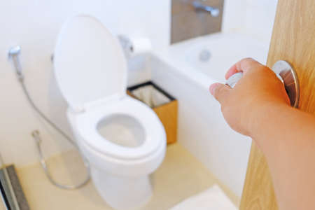 Asian right hand opening the door of bathroom and toiletの写真素材