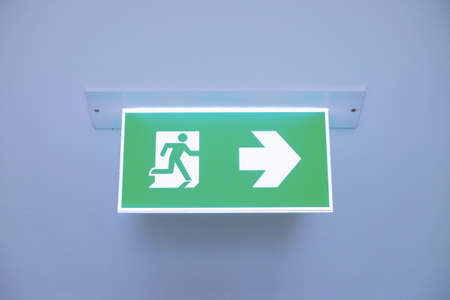 Front face raised view of green emergency fire exit sign hanging on the ceiling