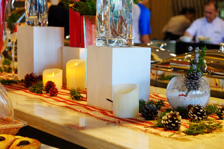 Candles and conifer fruit decoration on Christmas event in a dining placeの写真素材