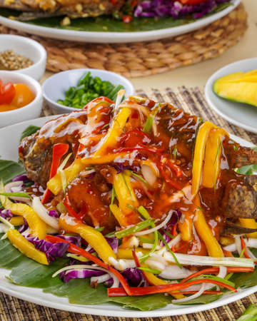 fried Nile Tilapia or Ikan Nila with mango sauce, Indonesian food and cuisine plate on bamboo trayの写真素材