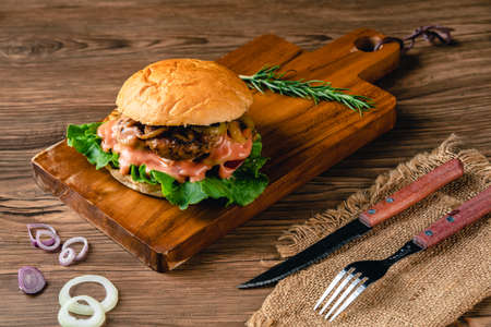 Fresh tasty chicken burger on wood table. Sandwich with chicken burger, tomatoes, pickled cucumber and fried egg. Fresh tasty chicken burger on wooden table.の写真素材