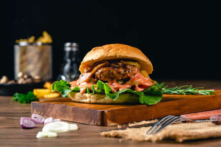Fresh tasty chicken burger on wood table. Sandwich with chicken burger, tomatoes, pickled cucumber and fried egg. Fresh tasty chicken burger on wooden table.の写真素材