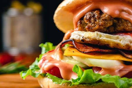 Fresh tasty chicken burger on wood table. Sandwich with chicken burger, tomatoes, pickled cucumber and fried egg. Fresh tasty chicken burger on wooden table.の写真素材