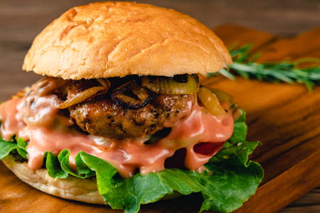 Fresh tasty chicken burger on wood table. Sandwich with chicken burger, tomatoes, pickled cucumber and fried egg. Fresh tasty chicken burger on wooden table.の写真素材