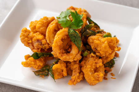 Stir Fried Squid with Salted Egg Yolk plating on white plate.の写真素材