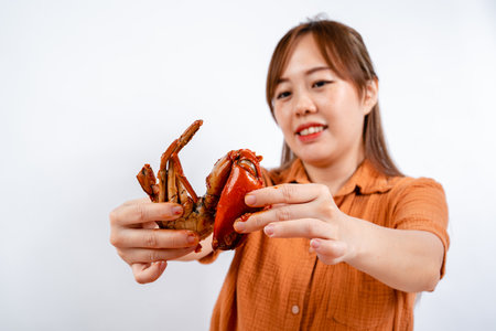 Young asian woman enjoys eating seafood, crab with padang sauce (Indonesian : Kepiting Saus Padang)...