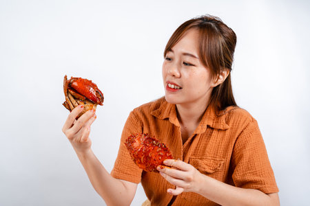 Young asian woman enjoys eating seafood, crab with padang sauce (Indonesian : Kepiting Saus Padang)...