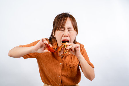 Young asian woman enjoys eating seafood, crab with padang sauce (Indonesian : Kepiting Saus Padang) isolated on white backgroundの写真素材