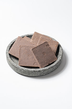 Traditional Indonesian Shrimp Paste Terasi on Mortal Stone isolated on white background, Fermented...