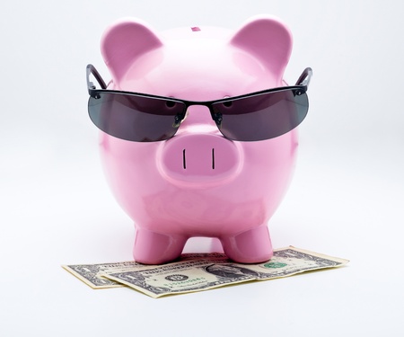 Piggy bank with sunglasses on U S  dollars illustrating concepts of moneyの写真素材