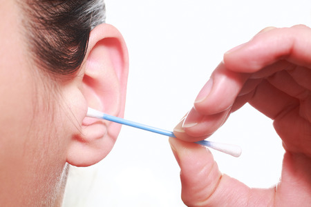 Photography closeup of a woman cleaning the ears with a cotton stalk;