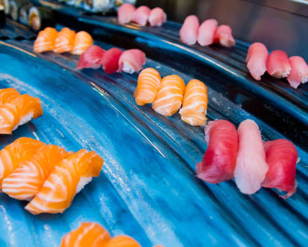 Various species of raw fish fillets rolled waiting to be used as ingredients in sushiの写真素材