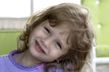 Little Girl Smiling at Camera with chairs in the background