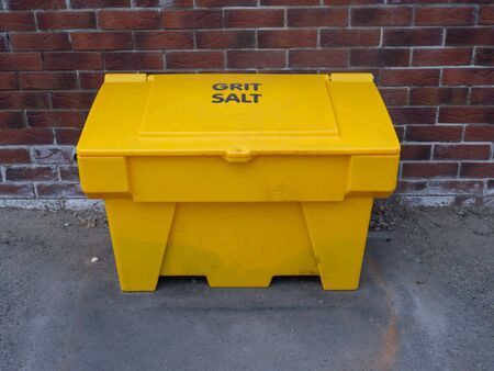 Yellow Grit Salt Bin against a brick wallの写真素材
