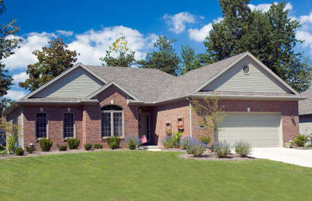 Beautiful brick ranch home against a blue cloudy sky.の写真素材