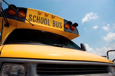 Close-up of the front of a school bus with a blue sky background.