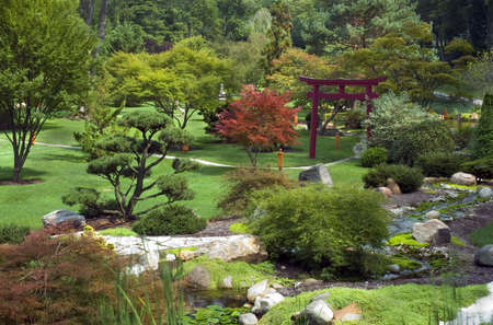 Beautiful and peaceful Japanese water garden. Complete with a red Torri  and several small waterfalls.の写真素材