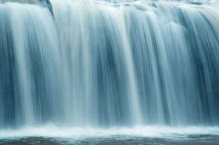 Isolation of part of a waterfall taken with a slow shutter speed to smooth the water, given a cool blue tint for effect. Beautiful detail in the water.の写真素材