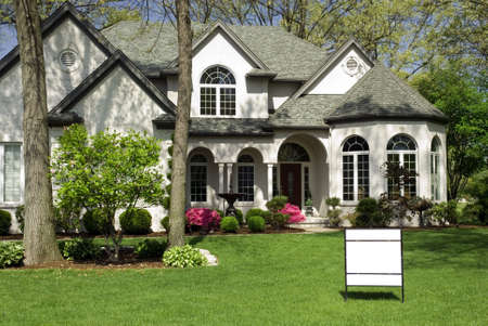 Beautiful white brick home featuring  complex architectural details and formal landscaping. A ready made FOR SALE sign in the yard to drop in your company name. の写真素材
