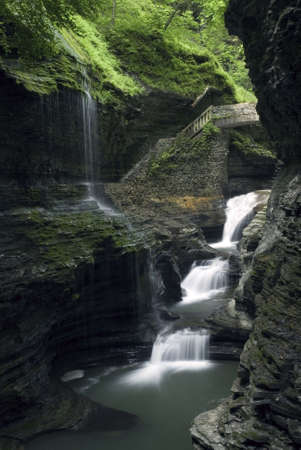 Rainbow Falls at Watkins  Glen state park in New York. Lush green moss and ferns along the gorge walls add to the beauty of the scene.  The gorge trail and stone bridges where constructed in the 1930's and blend in amazingly well with the natural surroundの写真素材